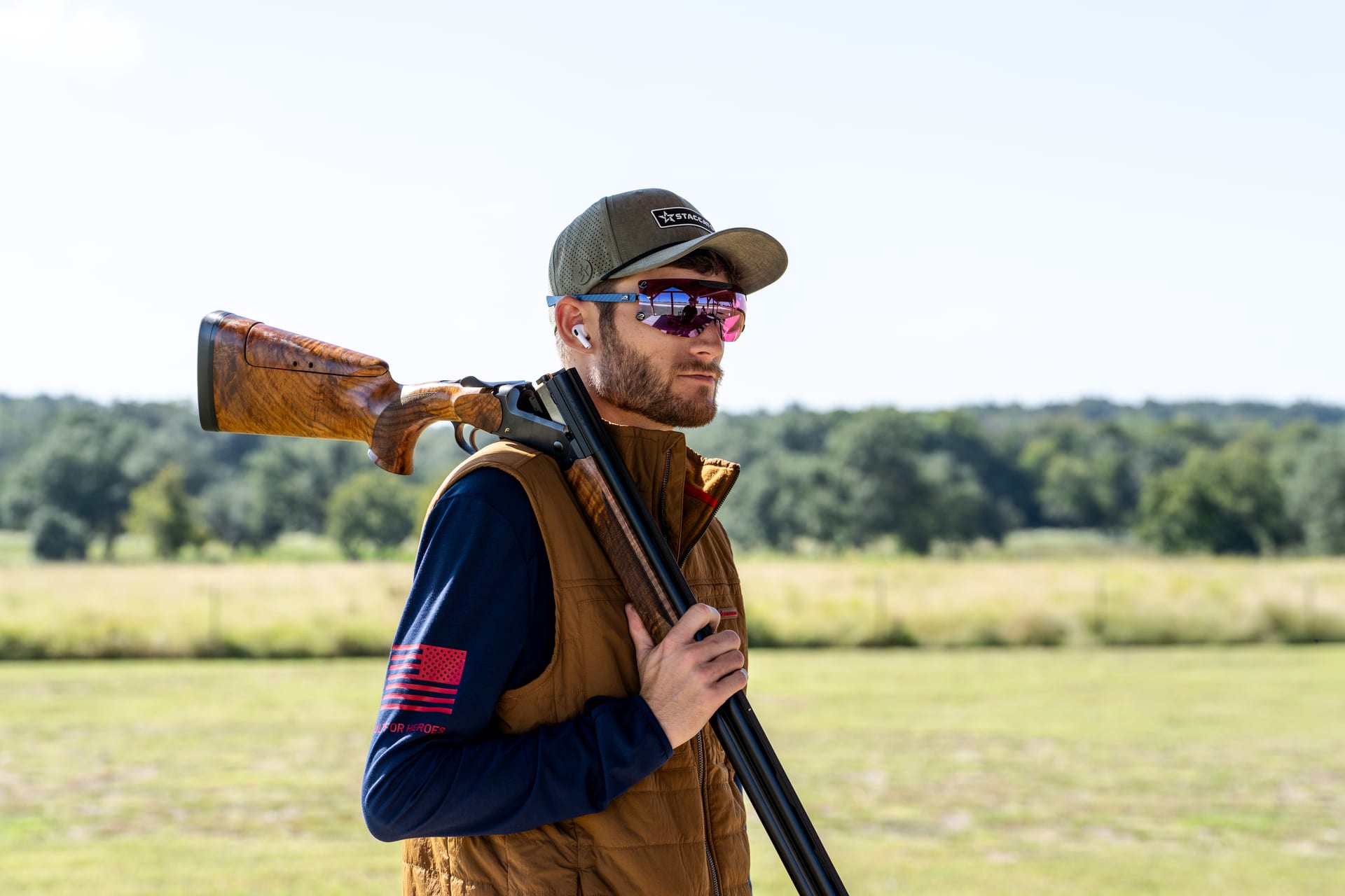 A shooter in a cap and shooting glasses on an open Texas field