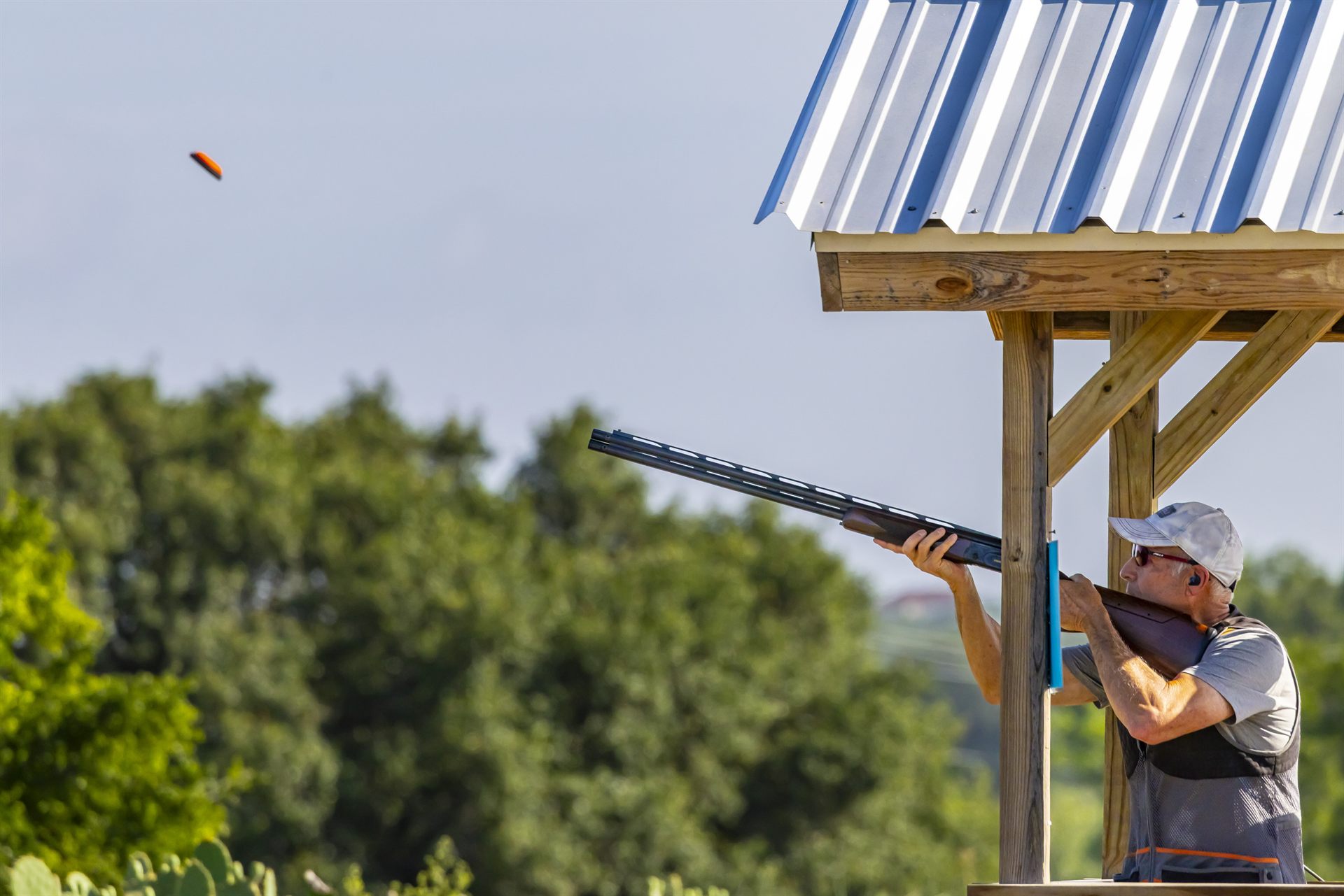A shooter mounting a shotgun at the covered Creek five-stand at Staccato Ranch Texas.